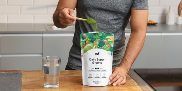 Poudre Greens avec une cuillère et un verre d'eau