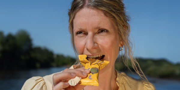 Femme mordant dans une barre chocolatée dans un emballage jaune