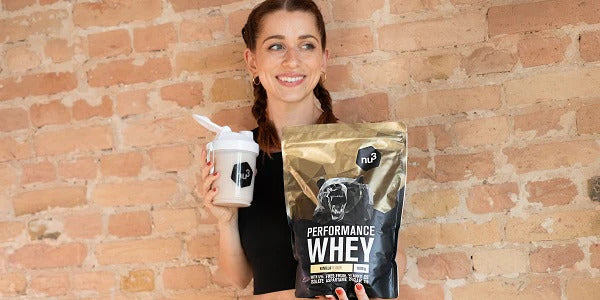Femme avec un paquet de whey et un shaker à la main