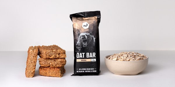 de gauche à droite : oat barre nu3 pour la prise de masse vegan, packaging de la oat bar nu3 et bol rempli de flocons d'avoine 