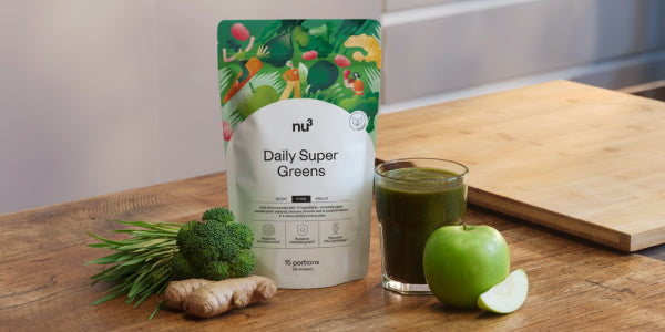 Légumes verts avec brocoli, pomme, gingembre et un verre contenant des légumes verts