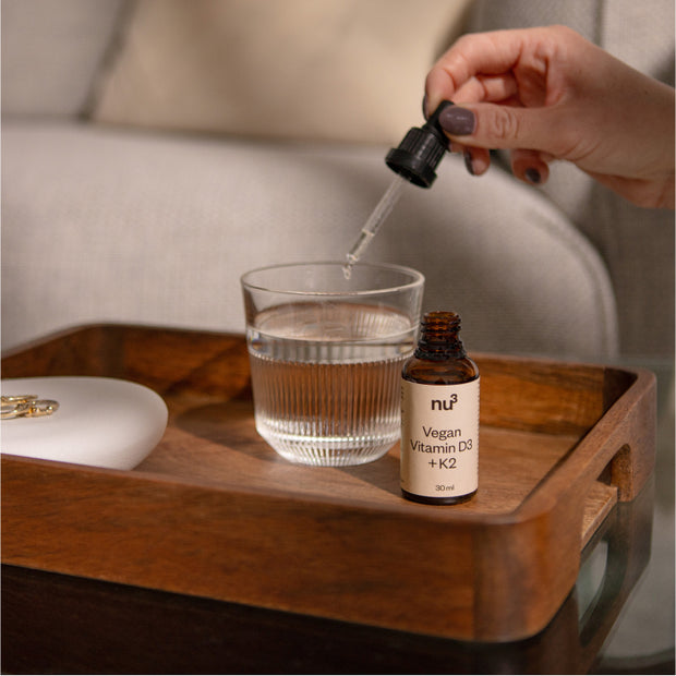 Gouttes de vitamine D végane dans un verre d'eau