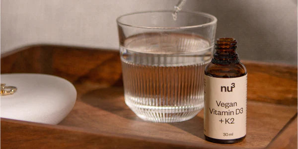 Vitamine D végane en gouttes avec un verre d'eau